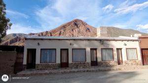 a white house with a mountain in the background at Tampu 2 alojamiento in Purmamarca +14 photos