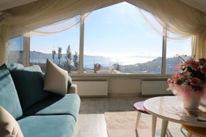 ein Wohnzimmer mit einem Sofa, einem Tisch und einem großen Fenster in der Unterkunft Deep Hotel in Istanbul