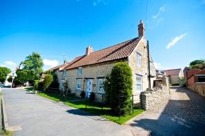 uma velha casa de tijolos com uma cerca em frente em Stunning Yew Tree Cottage em Westow