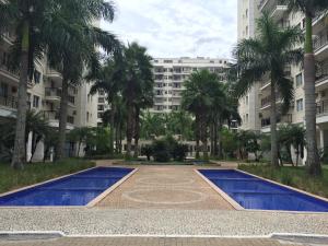 un gran edificio con palmeras y piscinas azules en Ap. Resort Recreio dos Bandeirantes, en Río de Janeiro