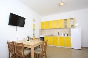 a kitchen with a wooden table and a kitchen with yellow cabinets at Apartments Jasmina in Novalja