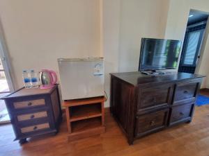 ein Zimmer mit einer Kommode und einem Fernseher sowie einer Kommode mit einem Kleid in der Unterkunft บ้านชยชิโต Chayachito Home Stay in Ban Mo