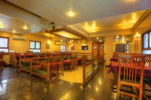 a restaurant with wooden tables and chairs and windows at Hotel Lonavla in Lonavala