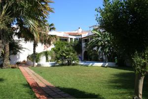 a house with a yard with palm trees and a sidewalk at Hotel Villa Mediterranea in Noto Marina
