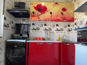 a kitchen with red cabinets and a red flower painting on the wall at Three rooms Apartment with all facilities in Tashkent