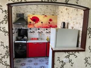 a small kitchen with a white refrigerator and red cabinets at Three rooms Apartment with all facilities in Tashkent +17 photos