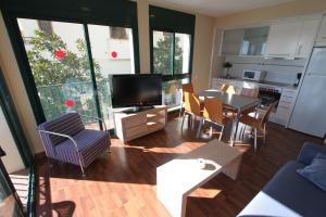 a living room with a television and a table and chairs at ACP Cambrils Puerto Apartamentos in Cambrils