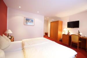 a hotel room with a white bed and a desk at Wald-Café Hotel-Restaurant in Bonn