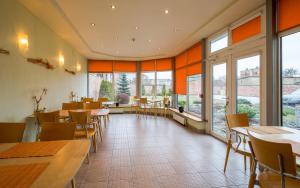 a restaurant with tables and chairs and large windows at Linda Hotel in Liepāja