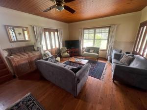 un salon avec deux canapés et une télévision dans l'établissement Shinglers Cottage, à Mayers Flat