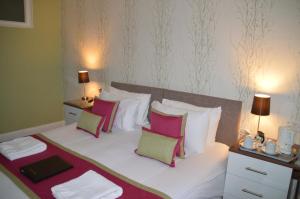 a bedroom with a large bed with pink and white pillows at Grosvenor House Hotel in Torquay