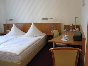 ein Hotelzimmer mit einem Bett und einem Tisch in der Unterkunft Pension Der kleine Nachbar (Inhaber: Christiane Klitzsch) in Gotha