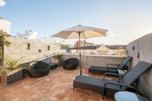 eine Terrasse mit Stühlen und einem Sonnenschirm auf dem Balkon in der Unterkunft SevillaHome- Ave Cesar in Sevilla