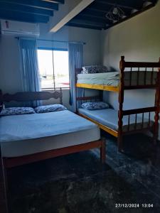 two bunk beds in a room with a window at Apartamento Encantador Praia da Pinheira in Palhoça
