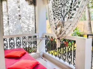 a balcony with a red bed and a window at The YelloMello House 1BHK fast Wi-Fi AC Pet-Friendly Cosy Cottage in Mandrem
