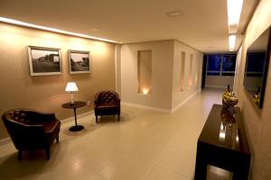 a lobby with chairs and a table and a lamp at Tri Hotel Xanxerê in Xanxerê