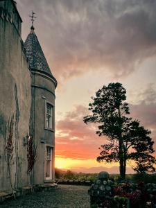 an old building with a tree in front of a sunset at Glencruitten House in Oban