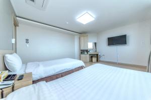 a hotel room with two beds and a flat screen tv at Jungmoon City Hotel in Seogwipo