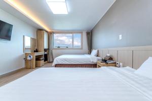 a hotel room with two beds and a window at Jungmoon City Hotel in Seogwipo