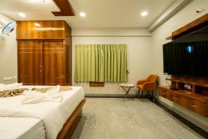 a bedroom with a bed and a flat screen tv at SID Royale in Gachibowli