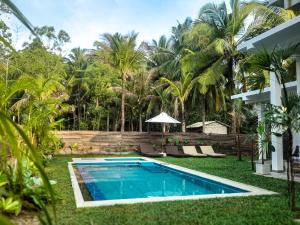 a swimming pool in the yard of a house with palm trees at VODA Hotel in Galle