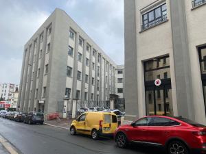 ein rotes und gelbes Auto, das vor einem Gebäude geparkt ist in der Unterkunft Le Passementier, T2 duplex grand volume parking souterrain wifi Netflix in Saint Etienne