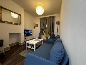 a living room with a blue couch and a table at Grove Rooms 2 in London