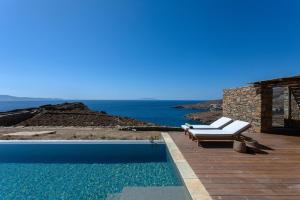 a swimming pool with a bench and the ocean at Villa Meltemi in Kardiani