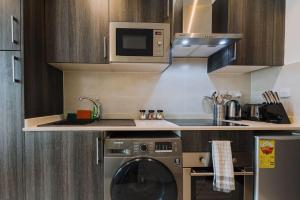 une cuisine avec un lave-linge et un micro-ondes dans l'établissement Luxury Studio at Embassy Gardens- Prime Location and Convenient, à Accra