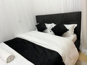 a bed with black and white sheets and pillows at Tranquil Luxury Stay, Utawala, JKIA View in Nairobi