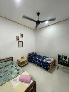 a bedroom with two beds and a ceiling fan at D'Padang KB Homestay in Kuala Berang +4 photos