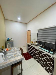 a kitchen with a table and a tv on a wall at D'Padang KB Homestay in Kuala Berang