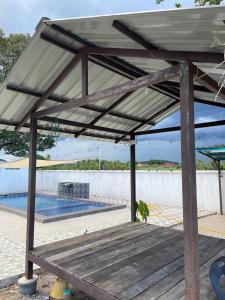 a wooden bench under a pavilion next to a swimming pool at D'Padang KB Homestay in Kuala Berang