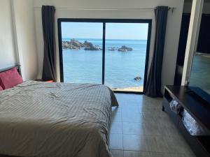 a bedroom with a large window with a view of the ocean at Alice house in Ko Bu Bu