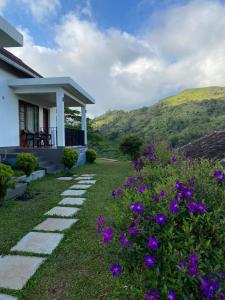 ein Haus mit einem Garten mit lila Blumen in der Unterkunft Sylvan Retreat - Luxury Mountain Cottages in Vagamon + 37 Fotos