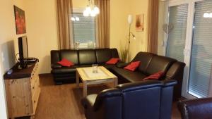 a living room with a black leather couch and a table at Haus Seeblick in Alt Schwerin
