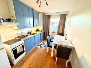 een keuken met blauwe kasten en een tafel met stoelen bij DP Apartments Vaasa III in Vaasa +9 foto's