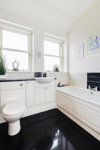 a white bathroom with a toilet and a tub and a sink at Luxury Seaview Gated Penthouse located near Edinburgh in Kirkcaldy