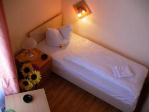 a small bedroom with a white bed and a table at Hotel garni Djaran in Offenbach