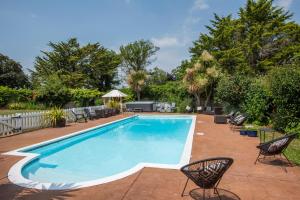 Una gran piscina con sillas y árboles. en Tarka Woodland Cabin, en Littleham