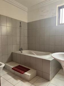 a white bathroom with a tub and a sink at Renda Residence Apartment in Takoradi +27 photos