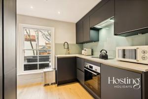 a kitchen with black cabinets and a microwave at The Loft - 1 Bed Luxury Apartment with Bathtub in Henley on Thames +11 photos