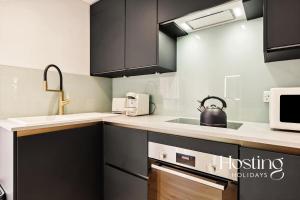 a kitchen with black cabinets and a tea kettle on the counter at The Loft - 1 Bed Luxury Apartment with Bathtub in Henley on Thames