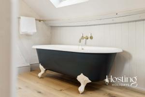 eine Badewanne mit einem Wasserhahn im Bad in der Unterkunft The Loft - 1 Bed Luxury Apartment with Bathtub in Henley on Thames