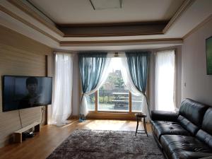 un salon avec un canapé et une grande fenêtre dans l'établissement 제주동쪽숙소 제주곶자왈별장 ForestGarden TheHouseOfCottonClouds, à Jeju