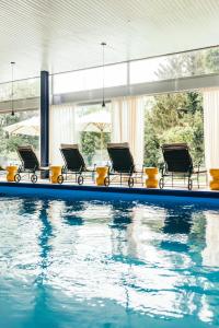 a swimming pool with a row of chairs next to it at Garden Hotel Reinhart in Prien am Chiemsee