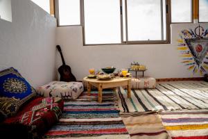 a living room with a table and a guitar at Ossmon Surf House - Anza in Agadir +107 photos