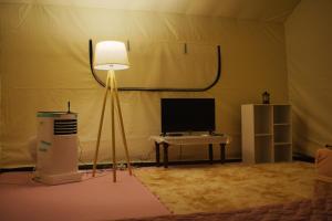 una stanza con lampada, monitor e tavolo di Hawun Glamping with Private Pool a Tamparuli