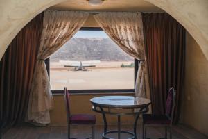 a table and chairs in front of a window with an airplane at Bait Ali in Wadi Rum