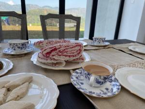 a table with plates of food and cups of coffee at Moragolla Estate Bungalow Kothmale in Gampola